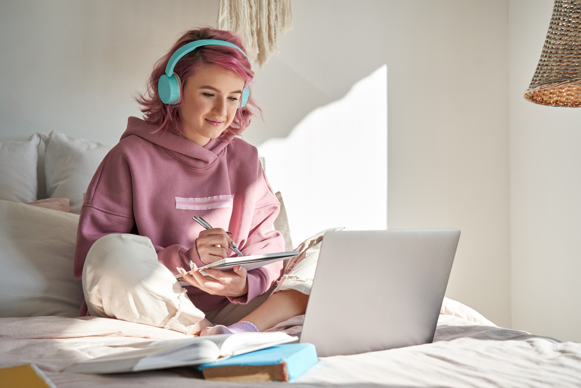 Teen Girl Student with Pink Hair Studying Online in Bed